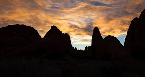 Low angle view of silhouette rock formations against sky during sunset