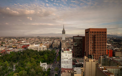 High angle view of city buildings against cloudy sky