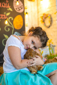 The girl is holding a little rabbit in her arms