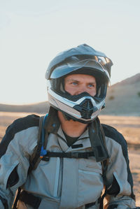 Portrait of man on motorcycle in desert during sunset