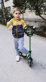 Boy with push scooter standing on road
