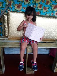 Cute girl holding book while sitting at home