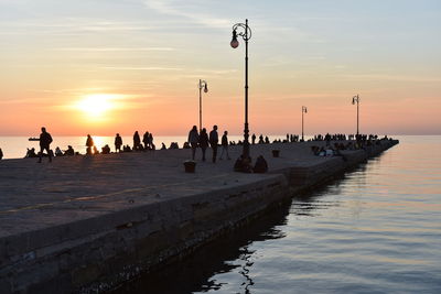 Silhouette people on beach against sky during sunset