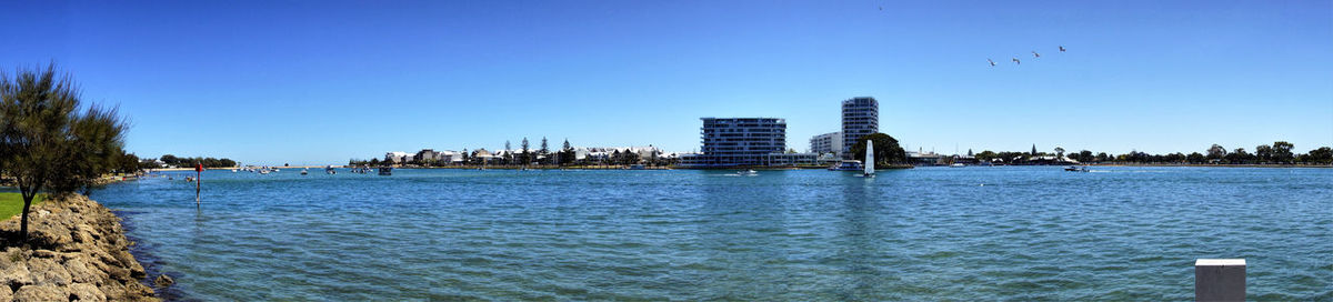 Sea by buildings against clear blue sky