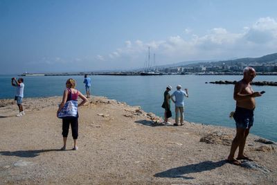 Rear view of people at beach against sky