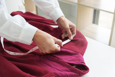 Midsection of woman holding red while sitting on bed