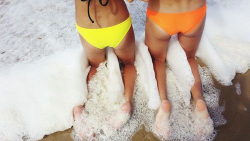 Low section of women kneeling on beach