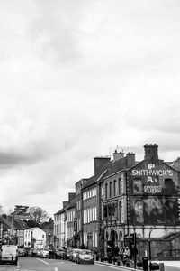 Buildings by road in city against sky