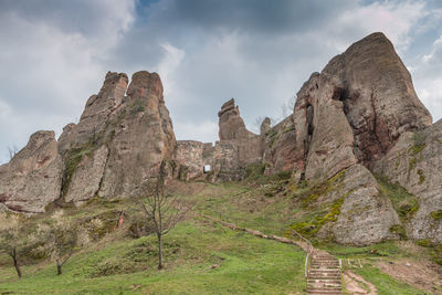 Rock formations on landscape against cloudy sky
