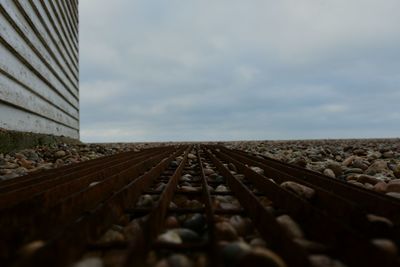 Surface level of railroad track against cloudy sky