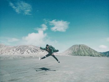 Man jumping in mid-air on land against sky