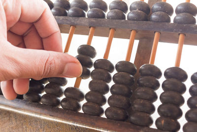 Cropped hand playing with abacus against white background