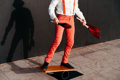 Cropped unrecognizable agile professional young male circus performer juggling clubs and balancing on board