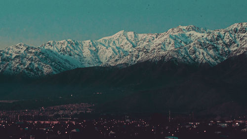 Aerial view of snowcapped mountains against sky in city