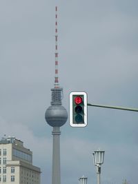 Low angle view of fernsehturm and road signal against sky