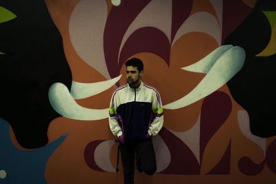 Portrait of young man standing against multi colored wall