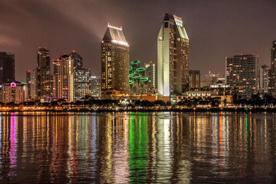 Illuminated buildings in city against sky at night