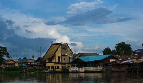 Houses by lake and buildings against sky