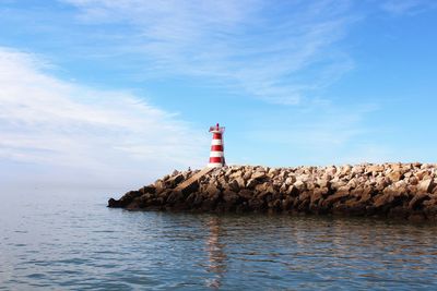 Lighthouse by sea against sky