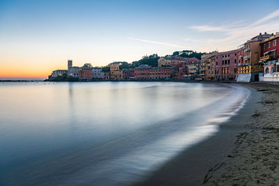 Town by sea against sky at sunset