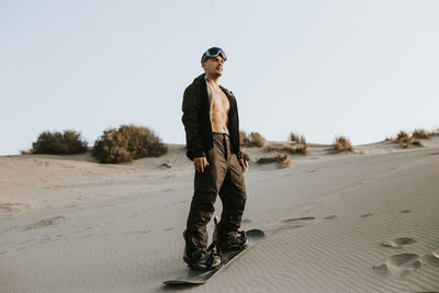 Young man wearing sandboard while standing on sand at almeria, tabernas desert, spain