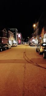 Cars on road by illuminated buildings in city at night