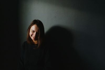 Smiling young woman looking down while sitting in darkroom at home