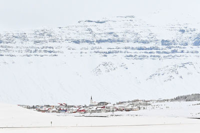 Text on snow covered land by sea against sky