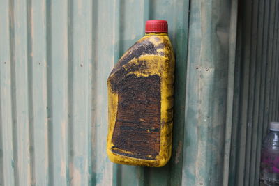 Close-up of old dirty bottle attached on corrugated iron