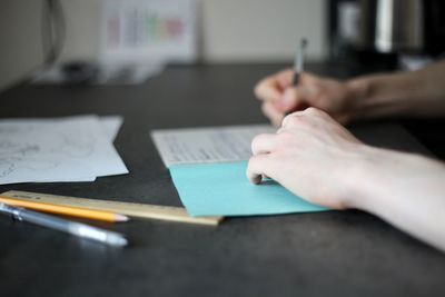 Cropped image of person hand holding paper on table