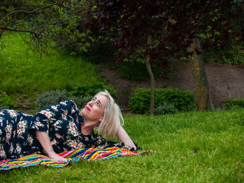 Mature woman lying on picnic blanket at park