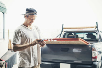 Carpenter using mobile phone by pick-up truck against clear sky