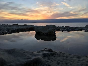 Rocks on beach against sky during sunset