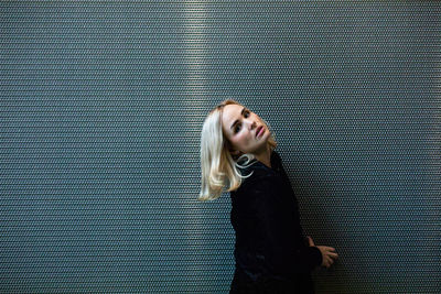 Portrait of beautiful woman standing against metallic wall