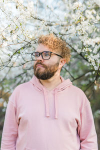 Portrait of young man standing against trees