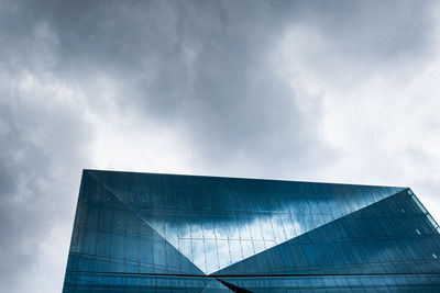 Glass building with reflection against cloudy sky