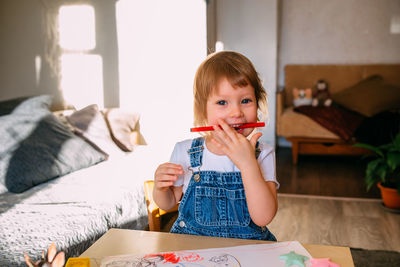 Small child at home at the children's table draws with felt-tip pens.