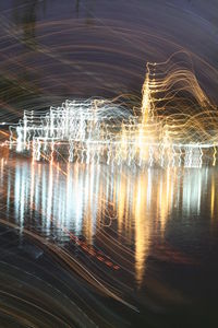 Close-up of illuminated reflection in lake against sky at night