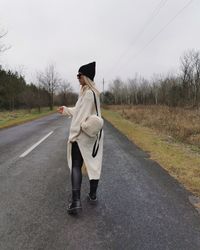 Full length of woman standing on road against sky