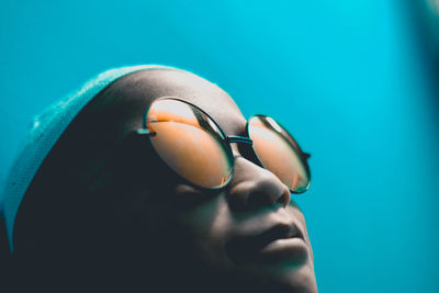 Close-up of girl wearing sunglasses against blue background