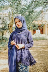 Portrait of woman standing against trees