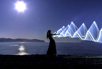 Woman standing by sea against sky