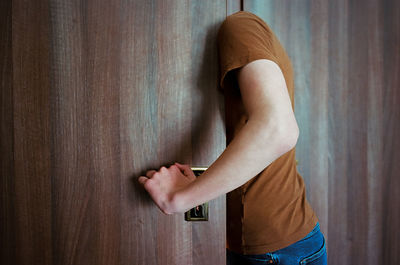 Midsection of young man standing against wall at home