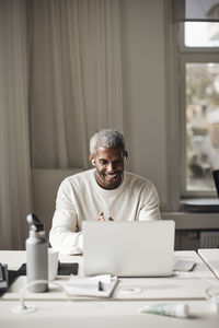 Young woman using laptop at desk in office