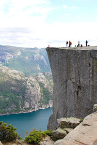 People on rocks by mountain against sky