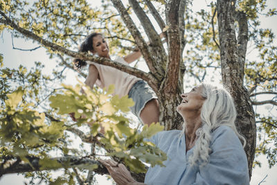 Mother and daughter having fun, climbing a tree