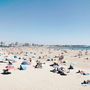 Group of people on beach against clear sky