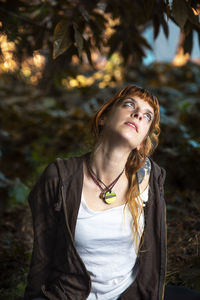 Thoughtful woman standing against plants