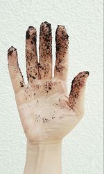 Cropped messy hand by white wall