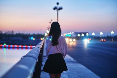 Rear view of woman standing on footpath on bridge